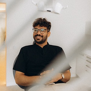 Patient with black glasses smiling in treatment chair