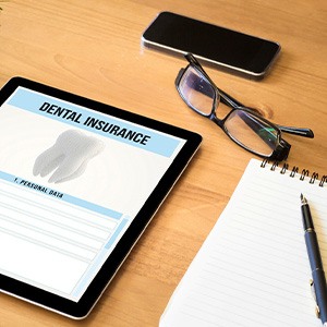 Dental insurance form on tablet next to notepad