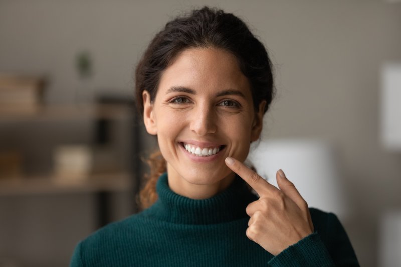 A young woman pointing to her beautiful smile