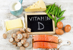 “Vitamin D” written on a chalkboard which is surrounded by cheese, mushrooms, and fish